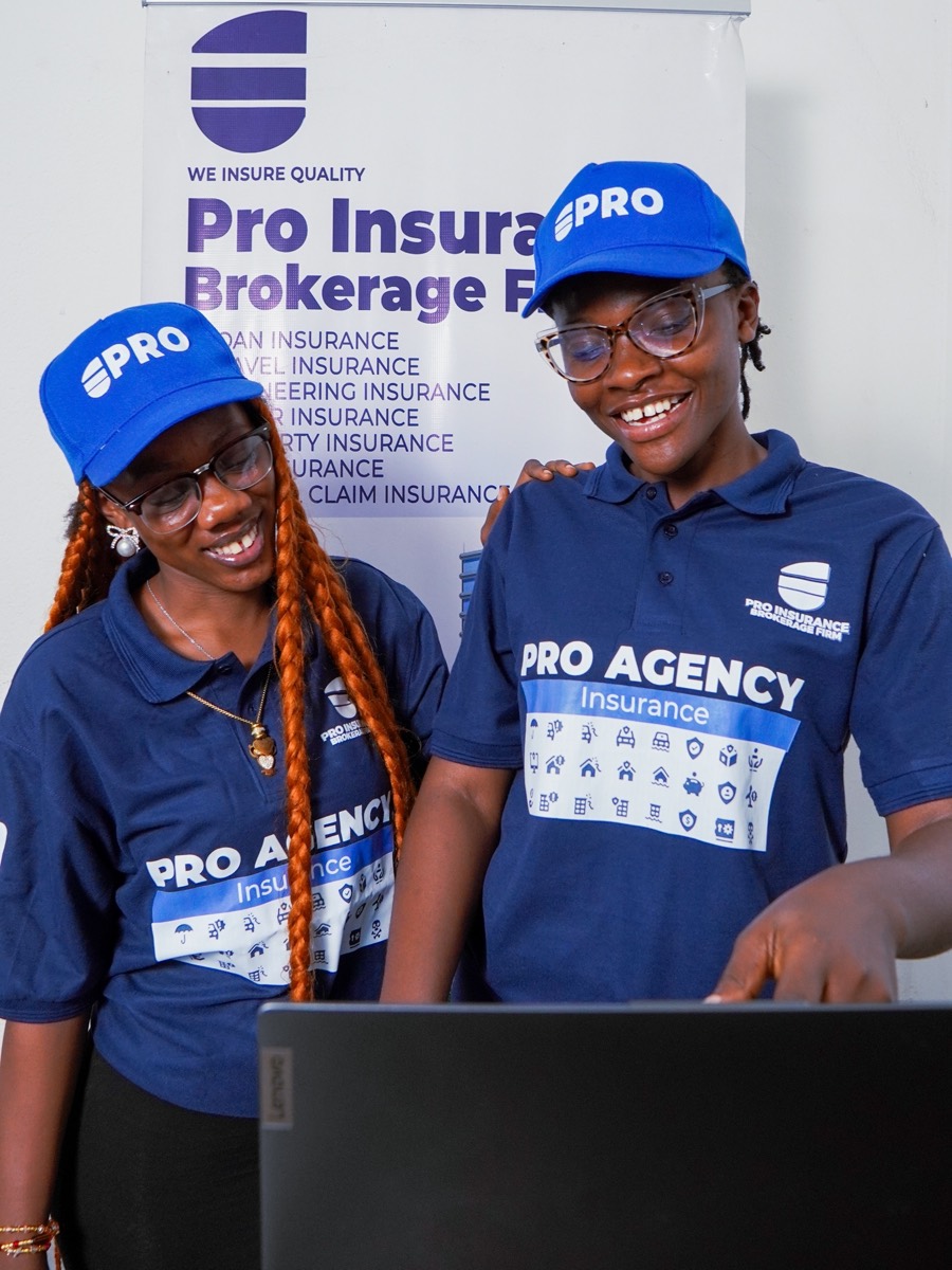 Two Pro-Insurance advisers working together at a laptop in front of the firm's branded banner